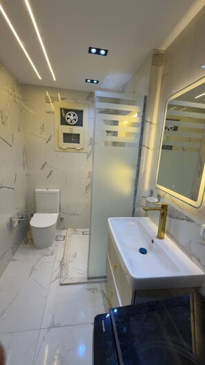 A modern bathroom with a toilet, sink, and shower. - Cozy 1-bedroom studio in tranquil Giza Governorate with AC (Giza Governorate)