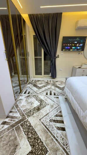 A hotel room with a bed, a television, a patterned carpet, and a sliding glass door. - Cozy 1-bedroom studio in tranquil Giza Governorate with AC (Giza Governorate)