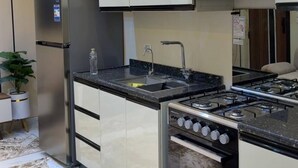 Una cocina moderna con electrodomésticos de acero inoxidable, horno empotrado y encimera negra.