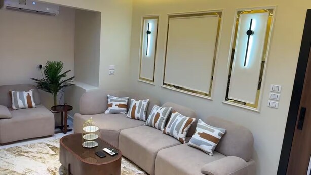 Una sala de estar moderna con un sofá color beige, una mesita de centro y una planta decorativa.