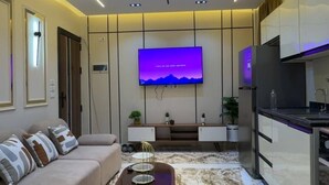 Una sala moderna con un sofá, una mesa de centro, un televisor de pantalla plana y una zona de cocina.