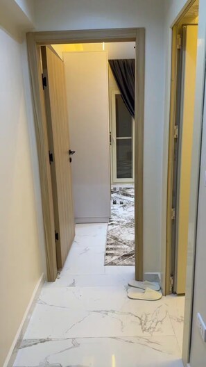 A hallway with a white marble floor leading to a door with a view of a snowy outdoor area. - Cozy 1-bedroom studio in tranquil Giza Governorate with AC (Giza Governorate)