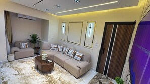A modern living room with a sofa, a coffee table, and a decorative mirror. - Cozy 1-bedroom studio in tranquil Giza Governorate with AC (Giza Governorate)