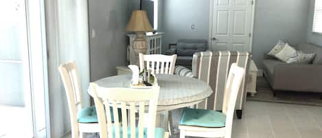 Un comedor con una mesa redonda, sillas blancas y un tapete estampado.
