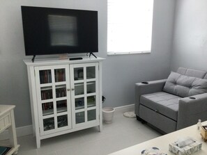 A living room with a white cabinet, grey sofa, and a television on top. - Cozy 1-bedroom apartment in fabulous Bonita Shores, Bonita Springs 1 mi to beach (Bonita Springs)