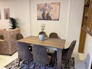 A dining area with a wooden table and cushioned chairs, a potted plant, and artwork on the wall. - Apartment in quiet neighborhood in Dokki (Giza Governorate)