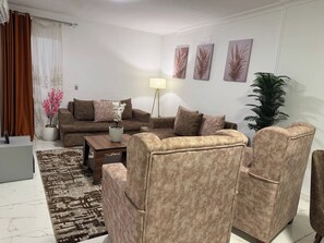 A living room with a sofa set, a coffee table, a lamp, and a potted plant. - Apartment in quiet neighborhood in Dokki (Giza Governorate)