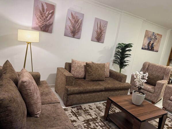 A living room with a sofa set, a coffee table, and decorative wall art. - Apartment in quiet neighborhood in Dokki (Giza Governorate)