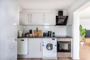 Cuina compacta amb rentadora, forn i cafetera.