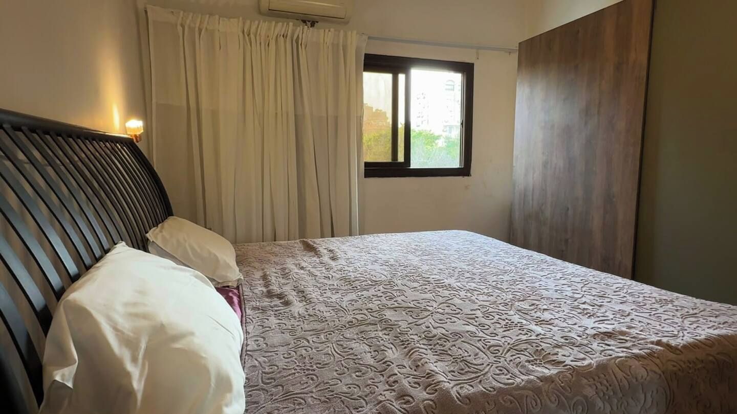 Een slaapkamer met een bed, een raam en gordijnen.