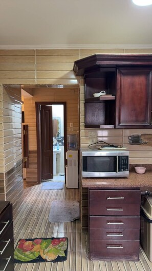 Una cocina con armarios de madera, un microondas y un refrigerador.