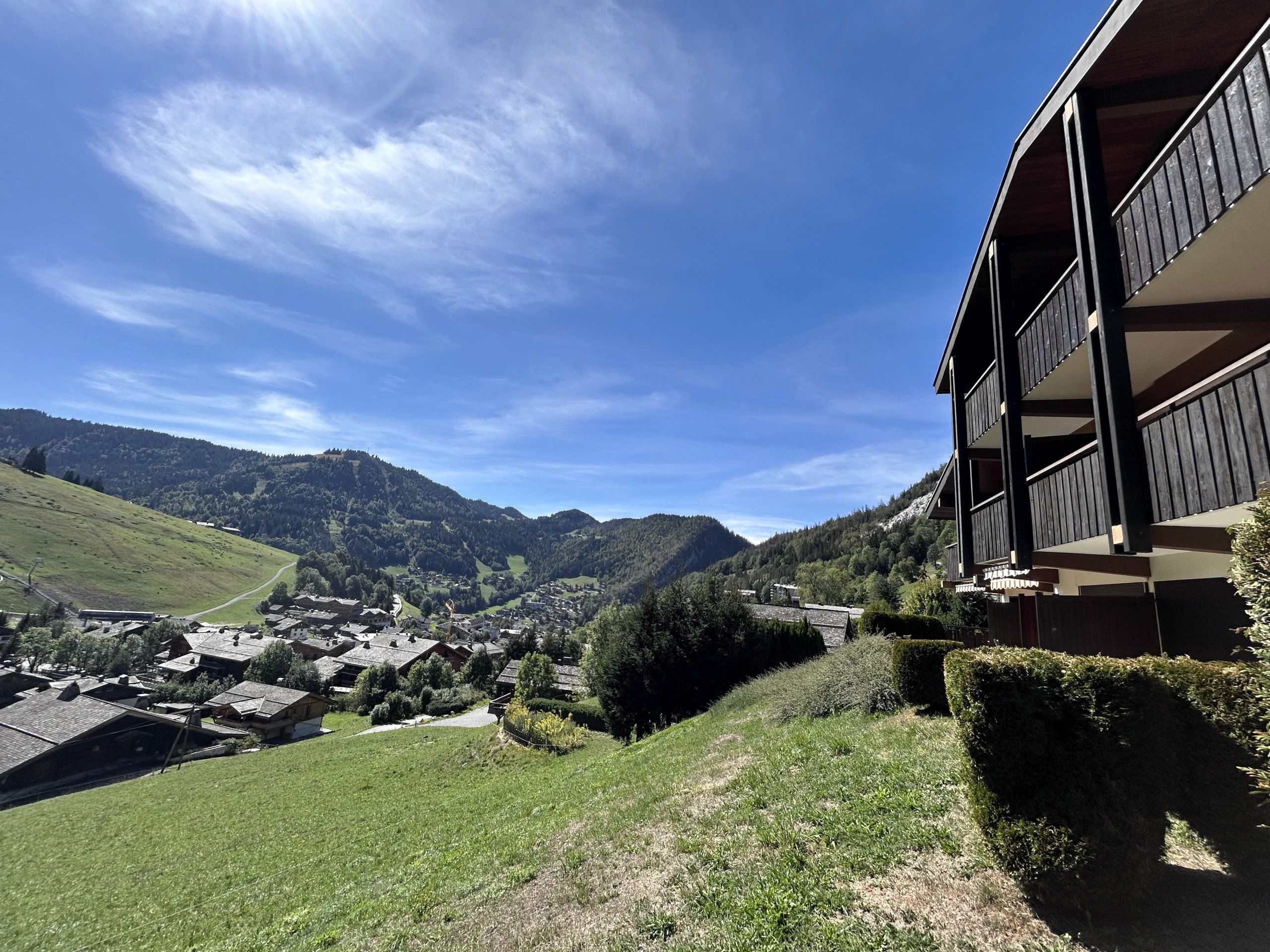 Un village de montagne aux maisons traditionnelles, avec un ciel dégagé et une vue sur les collines environnantes.