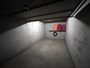 A dimly lit, concrete room with a shelf holding three bags. - NEW - NANT SOLEIL  A14 – Apartment with view, close to the village – Garage (La Clusaz)