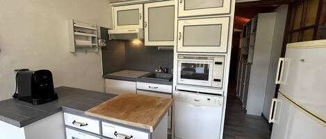 Een kleine keuken met witte kastjes, een magnetron, een broodrooster en een houten aanrecht.