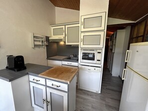 Eine kompakte Küche mit weißen Schränken, einer Mikrowelle, einem Toaster und einer Holz Arbeitsplatte.
