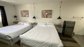 A hotel room with two single beds, a refrigerator, bedside tables, lamps, and abstract wall art. - Silverwood Lodge (Athol)