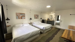 A hotel room with two beds, a desk, a mirror, and artwork on the walls. - Silverwood Lodge (Athol)