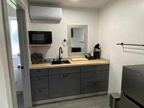 Ett kompakt kök med en inbyggd mikrovågsugn, en diskho och en kaffebryggare.
