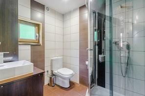 A modern bathroom with a glass shower enclosure, a toilet, and a sink. - Domki Za Wydmami (Mrzeżyno)