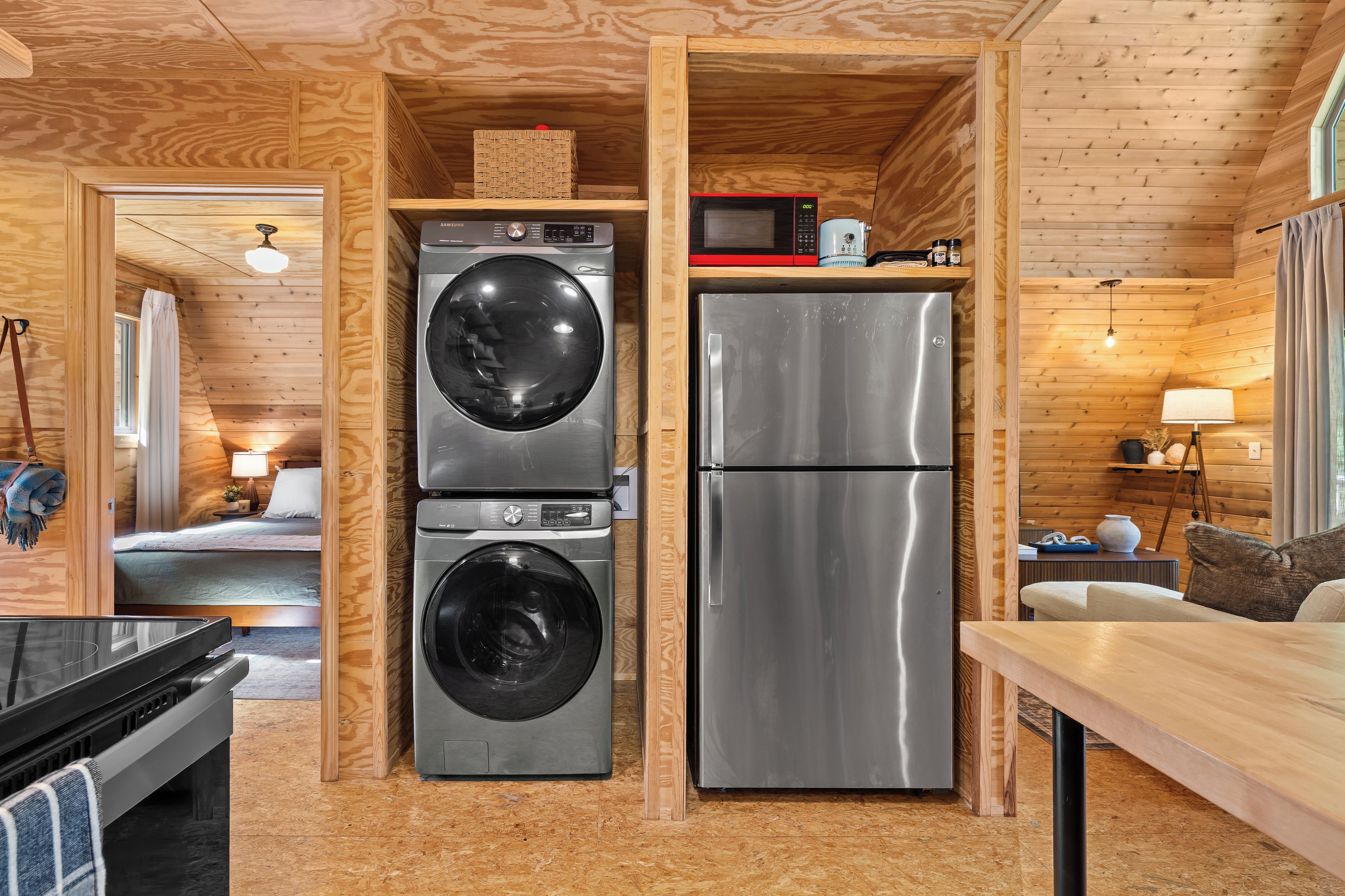 A compact kitchen with a stainless steel refrigerator, a washing machine, and a microwave.