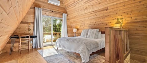 Una camera da letto con un letto, una scrivania, una sedia, una lampada e vista sull'esterno.