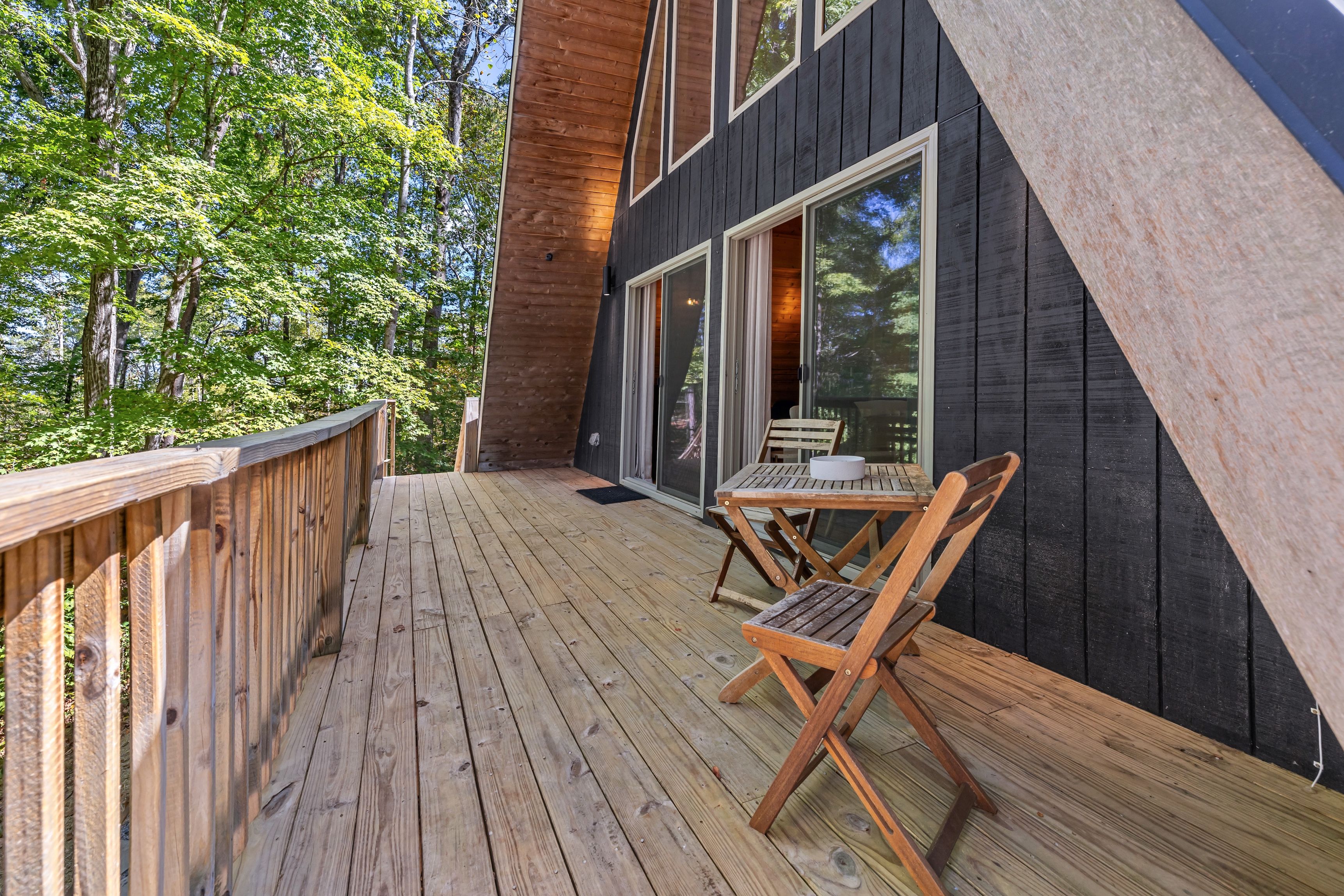 A wooden deck with a table and chairs, overlooking a forest.