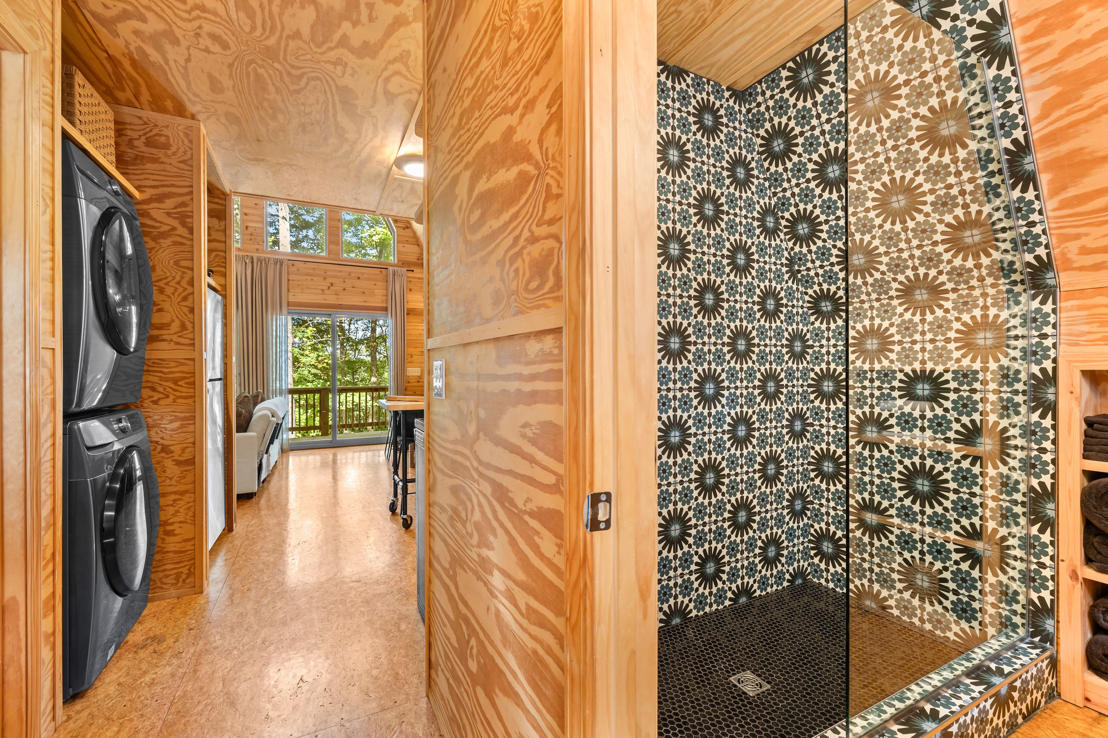 A wooden interior with a washing machine, a dining area with a view, and patterned tiles.