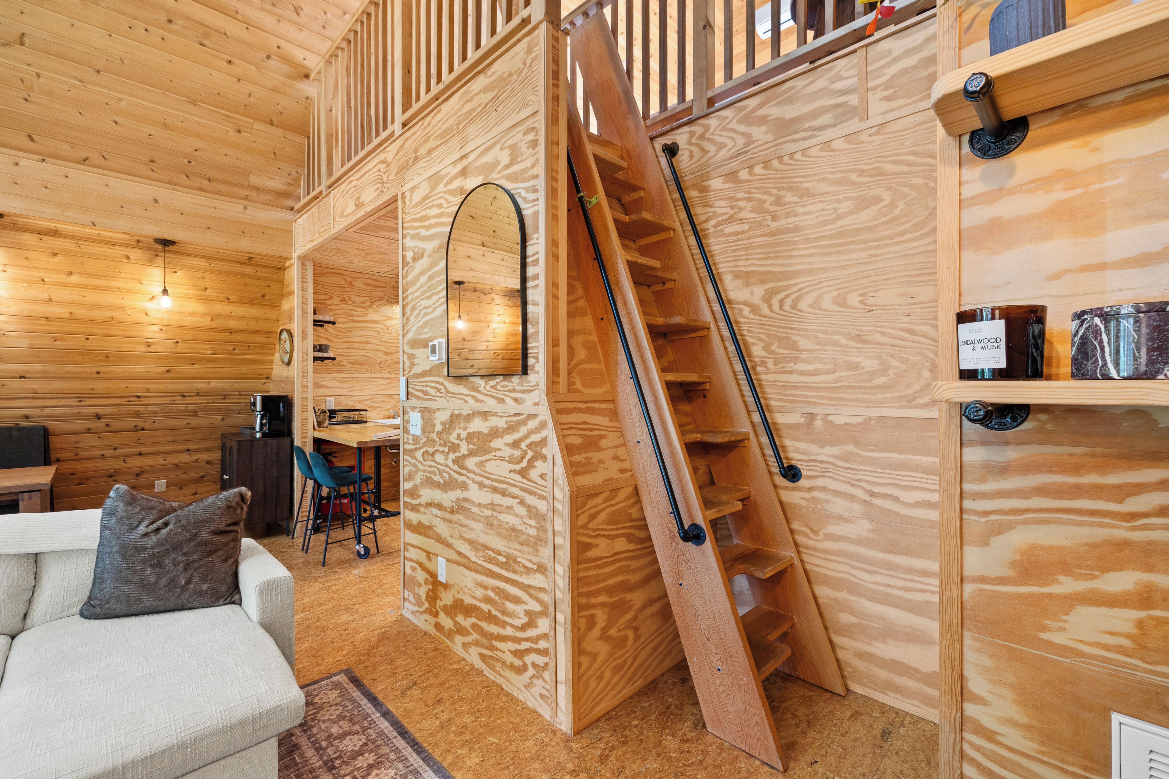 A wooden interior with a staircase, a sofa, and a coffee machine.