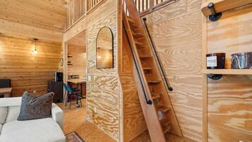 A wooden interior with a staircase, a sofa, and a coffee machine.