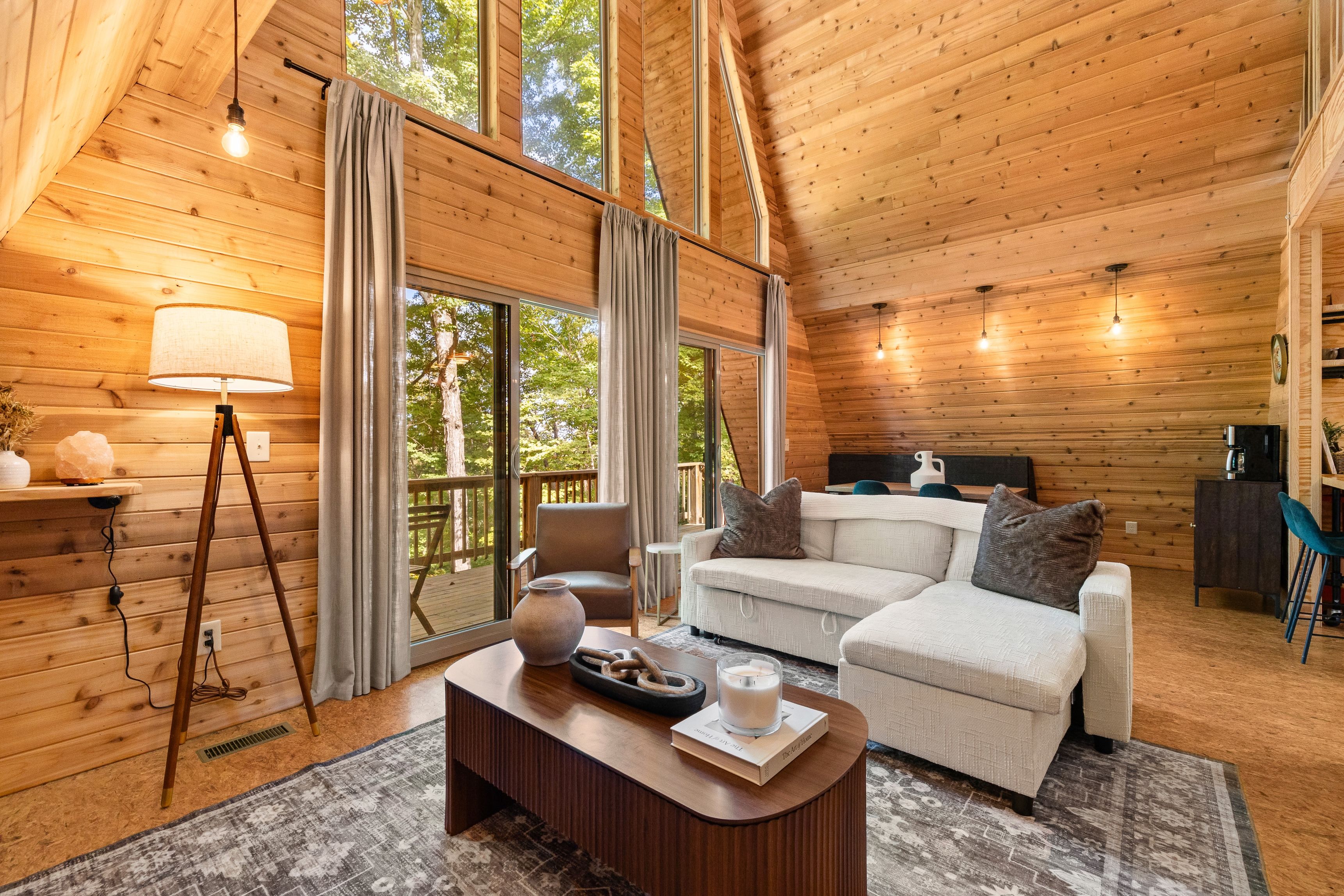 Interior acogedor de una cabaña, con paredes de madera, un sofá, una mesita de centro y una lámpara.