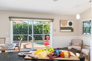 A dining area with a table set for a meal, featuring a variety of cheeses, meats, and fruits. - Heated Pool - 3BR Home in Marco Island - EV Charging (Marco Island)