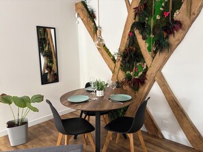A dining area with a round wooden table, black chairs, and a wall-mounted plant. - Ker Love Rennes Nature maison 4 personnes (Laillé)
