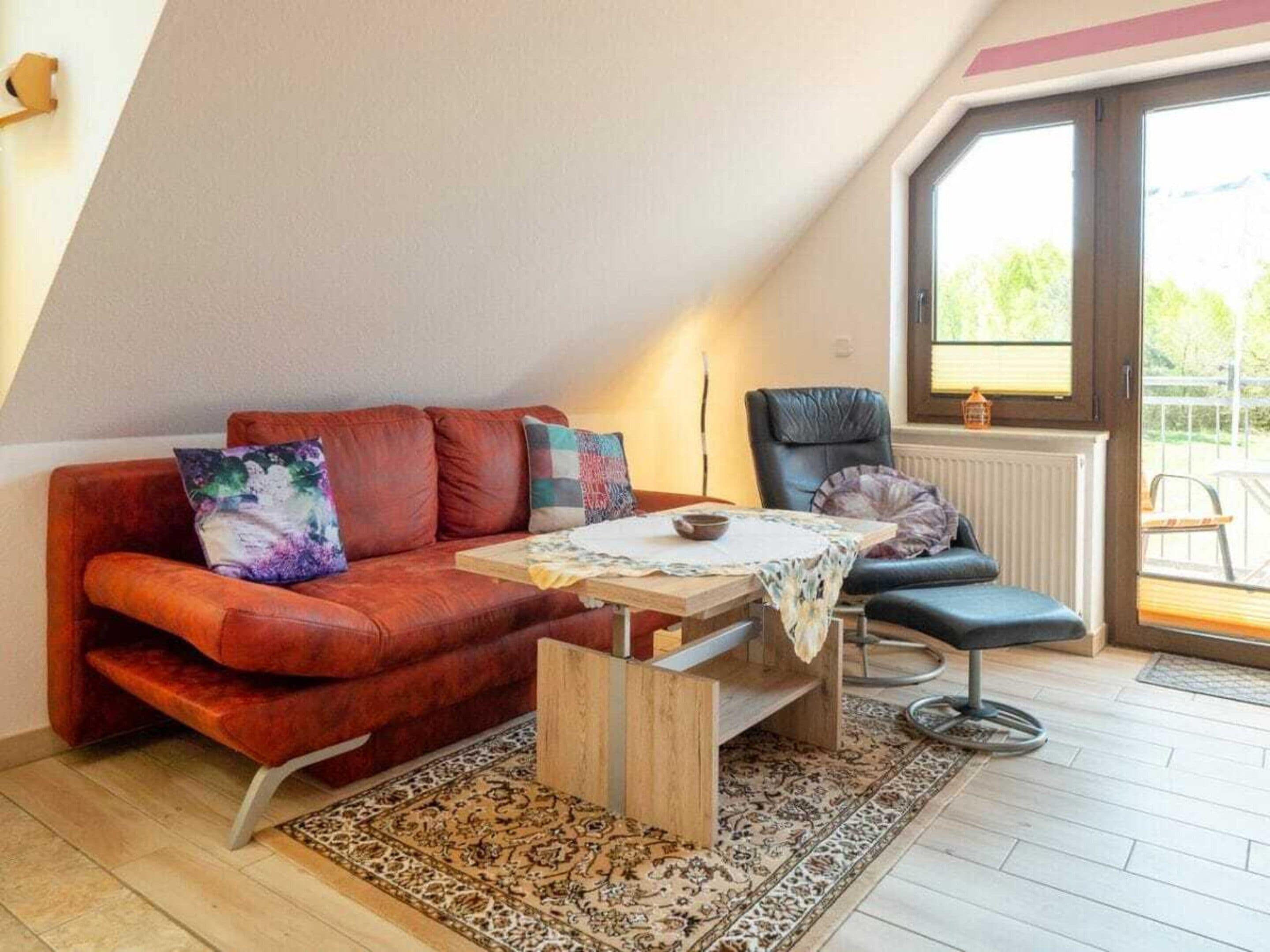 A cozy living room with a red sofa, a small table, and a blue chair.