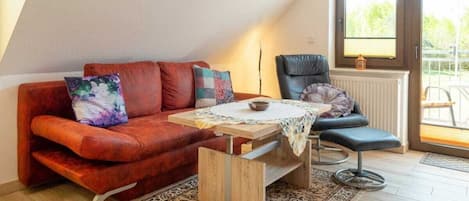 A cozy living room with a red sofa, a small table, and a blue chair.