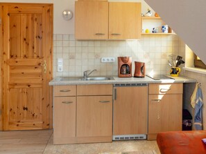Eine Küche mit Holzschränken, einer Spüle und einer Kaffeemaschine.