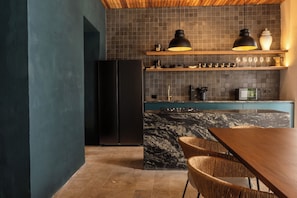 A kitchen with a black refrigerator, wooden cabinets, a marble countertop, and a dining area with a wooden table and chairs. - Vrbo Property (Cartagena de Indias)
