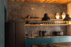 A modern kitchen with a dark tiled backsplash, wooden shelves, and pendant lighting. - Casa Alquimia—8 bedrooms (Cartagena de Indias)