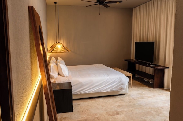 A hotel room with a bed, a television, a ceiling fan, and a wall-mounted light fixture. - Vrbo Property (Cartagena de Indias)