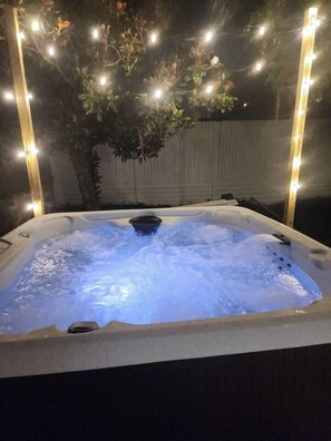 A hot tub with water jets, surrounded by string lights and a tree. - Modern Tampa Retreat Hot Tub  EV Charger Sleeps 8 (Tampa)