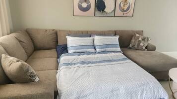 A living room with a sofa bed, a patterned throw blanket, and wall art.