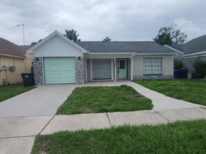 A residential house with a garage, a front door, and a driveway. - Modern Tampa Retreat Hot Tub  EV Charger Sleeps 8 (Tampa)
