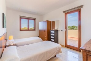 A bedroom with two beds, a wardrobe, a desk, a lamp, and a window with a view. - Holiday Home 'Can Bou' with Sea View, Wi-Fi and Air Conditioning (Ses Salines)