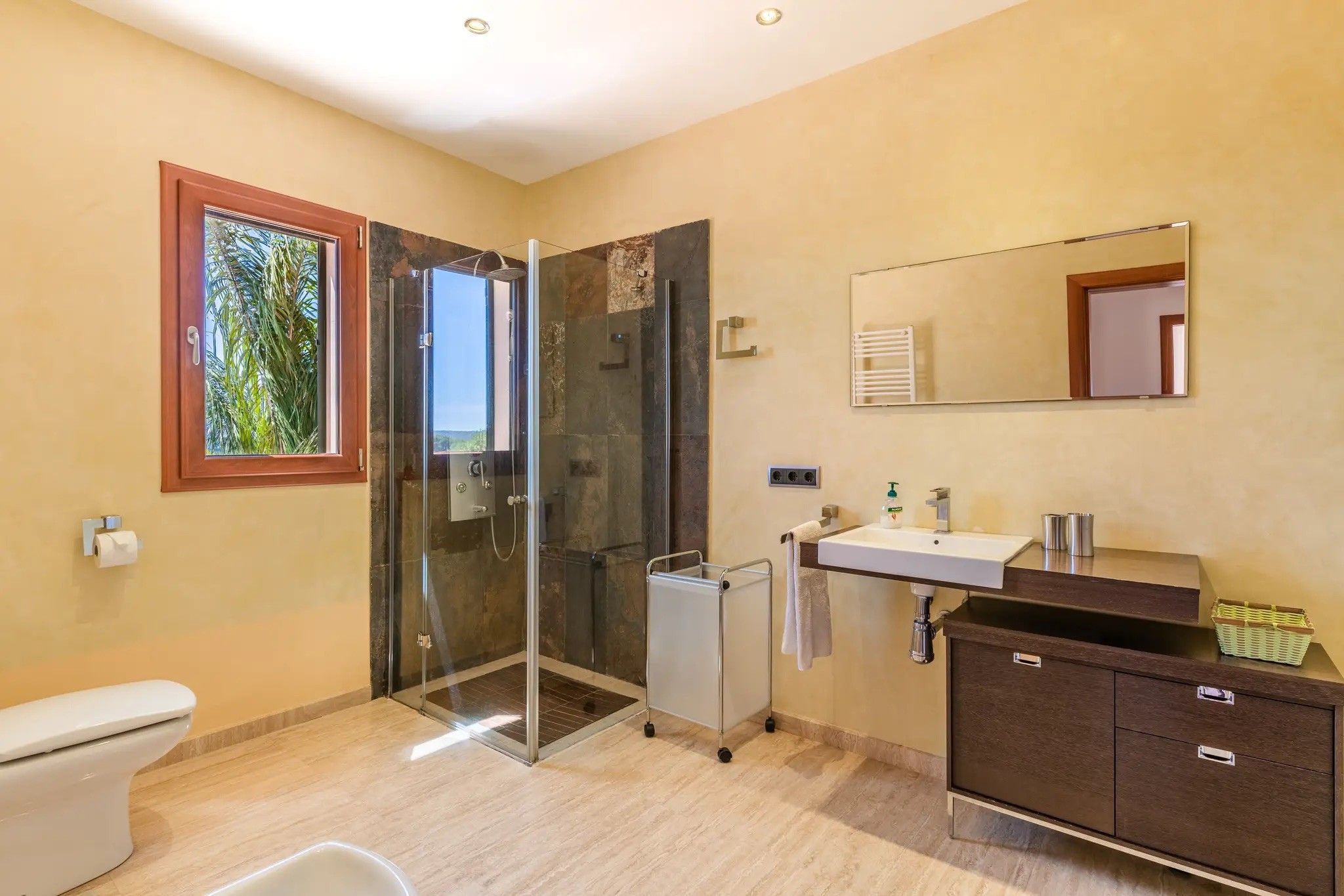 Een moderne badkamer met een douchecabine van glas, een wastafel met spiegel en een toilet.