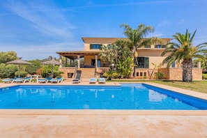 A two-story house with a swimming pool, outdoor seating, and palm trees. - Holiday Home 'Can Bou' with Sea View, Wi-Fi and Air Conditioning (Ses Salines)