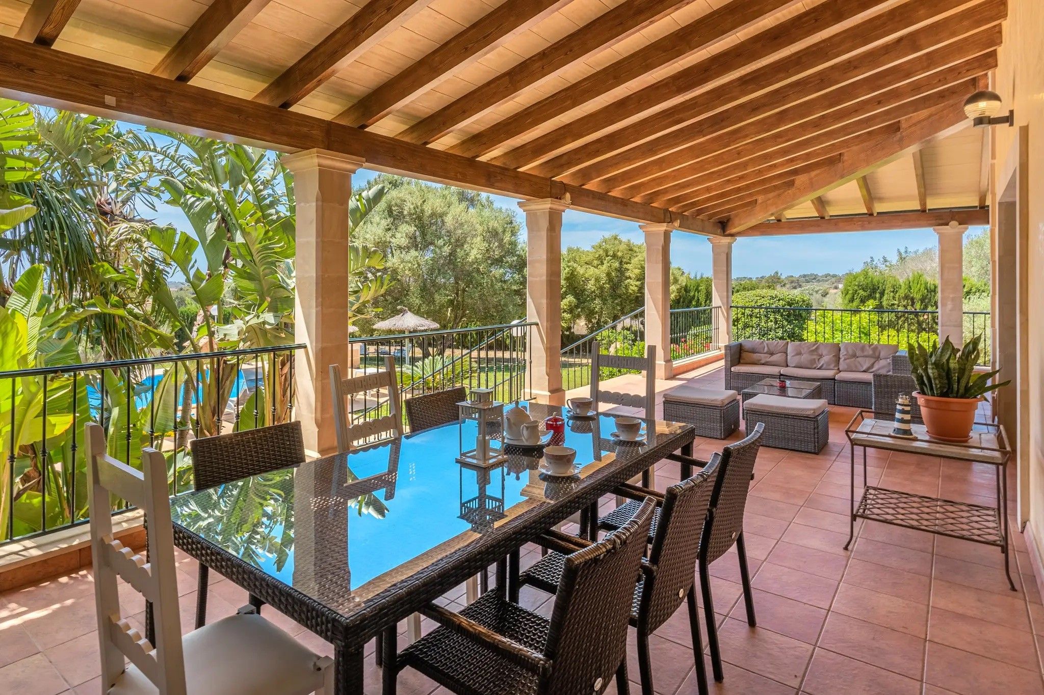 Un espacio al aire libre techado con mesa de billar, asientos y vista a la piscina.