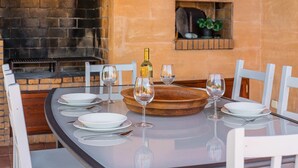 Mesa de jantar posta com pratos brancos, copos de vinho e talheres. Uma garrafa de vinho está sobre a mesa.