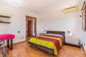 A bedroom with a bed, bedside tables, an air conditioning unit, a desk, and a chair. - Holiday Home 'Can Bou' with Sea View, Wi-Fi and Air Conditioning (Ses Salines)