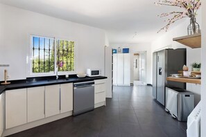A modern kitchen with a dishwasher, microwave, and refrigerator. - Private villa with a large pool and guest house | Casa J&J | Andalusia (Alhaurín el Grande)