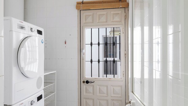 Un lavadero con lavadora Bosch, secadora y una puerta con ventana.
