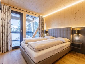 A bedroom with a large bed, a wooden ceiling, and a view of trees through a window. - Superior Chalet # 9 With Sauna & Hot Tub (Stadl-Predlitz)